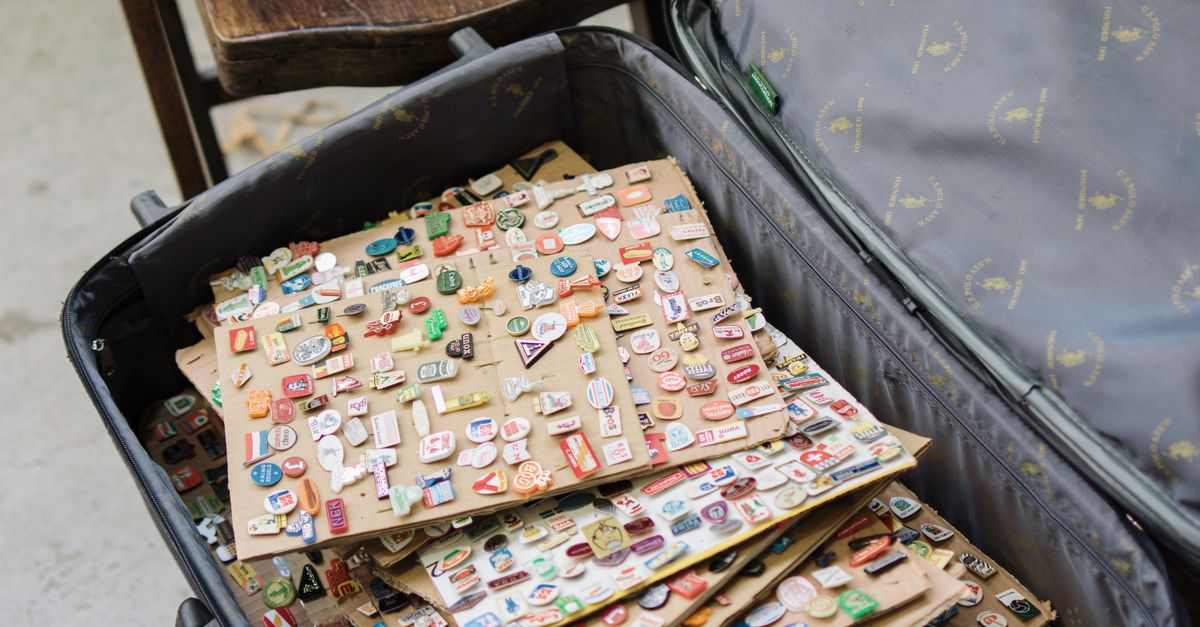 A diverse collection of vintage pins displayed in an open suitcase, showcasing travel and nostalgia themes.