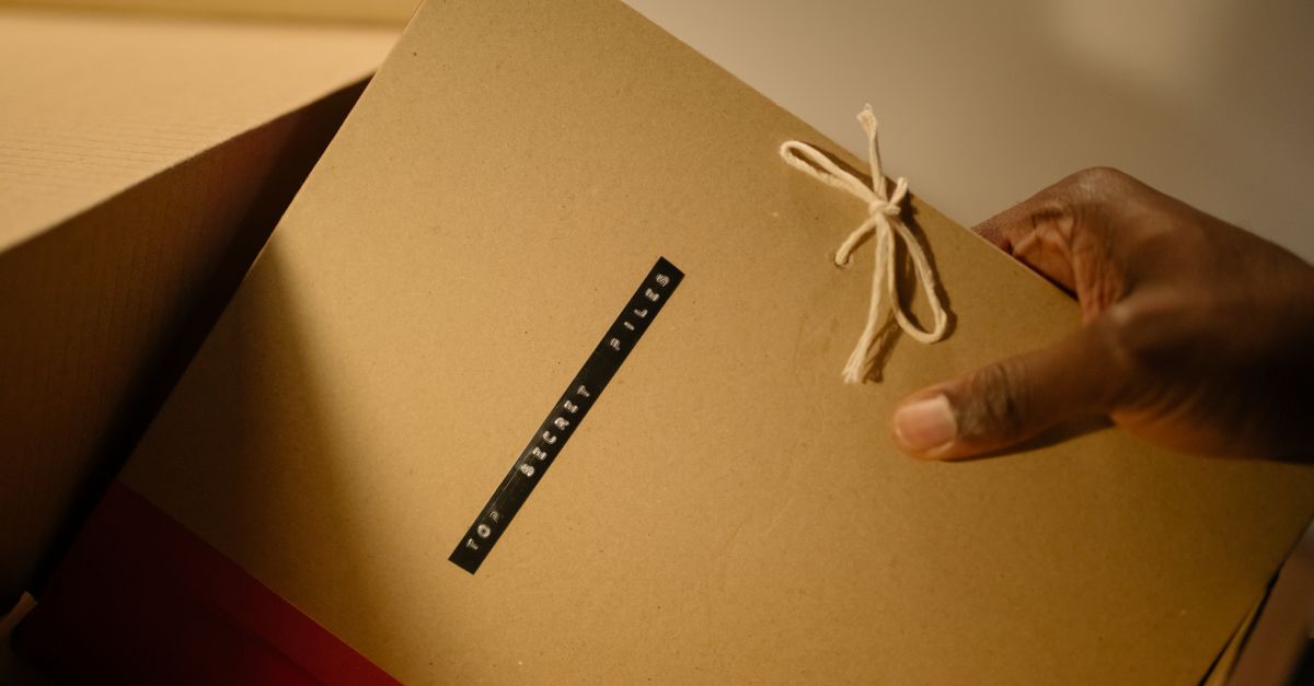 Close-up of hand holding top secret document folder in a box.