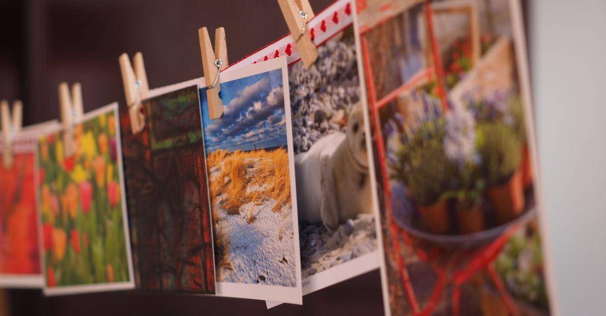 Colorful photographs and postcards clipped with wooden pins in a creative indoor arrangement.