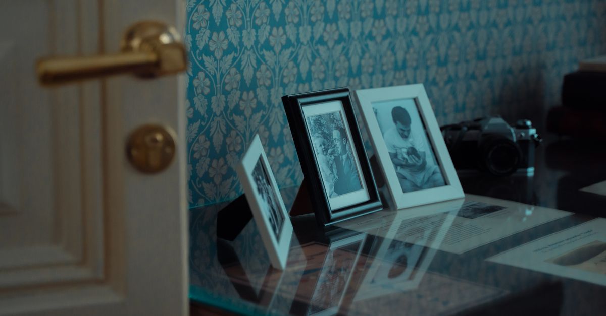 Elegant display of vintage photo frames and classic camera on glass table.