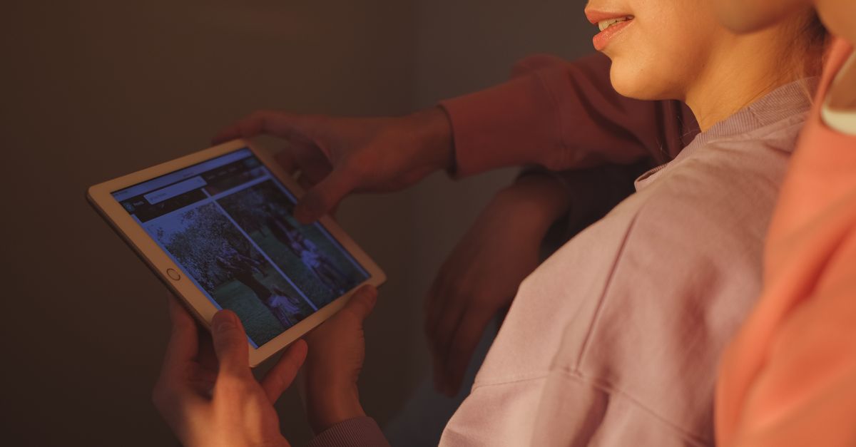A couple using a tablet together in a cozy indoor setting, enjoying technology.