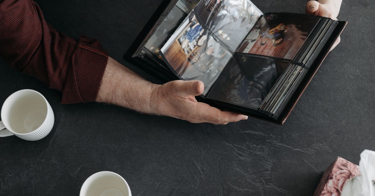 Hands holding a photo album with coffee cups, evoking memories and nostalgia.