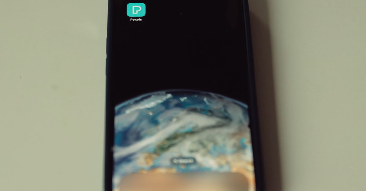Close-up of smartphone showing Earth wallpaper and Pexels app icon on screen.