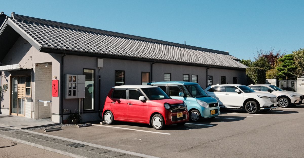 A charming coffee shop with parked cars under a clear blue sky in Inuyama, Japan.