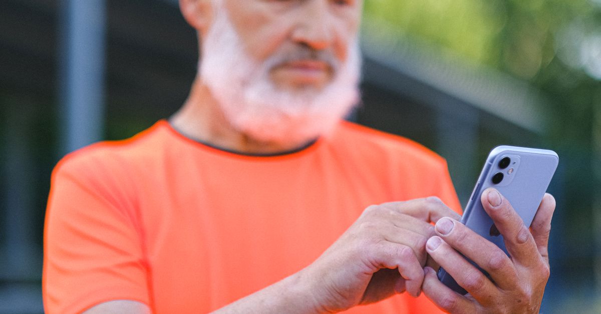 屋外でスマートフォンを操作する男性、隠しフォルダアプリの写真トラブルを扱う記事
