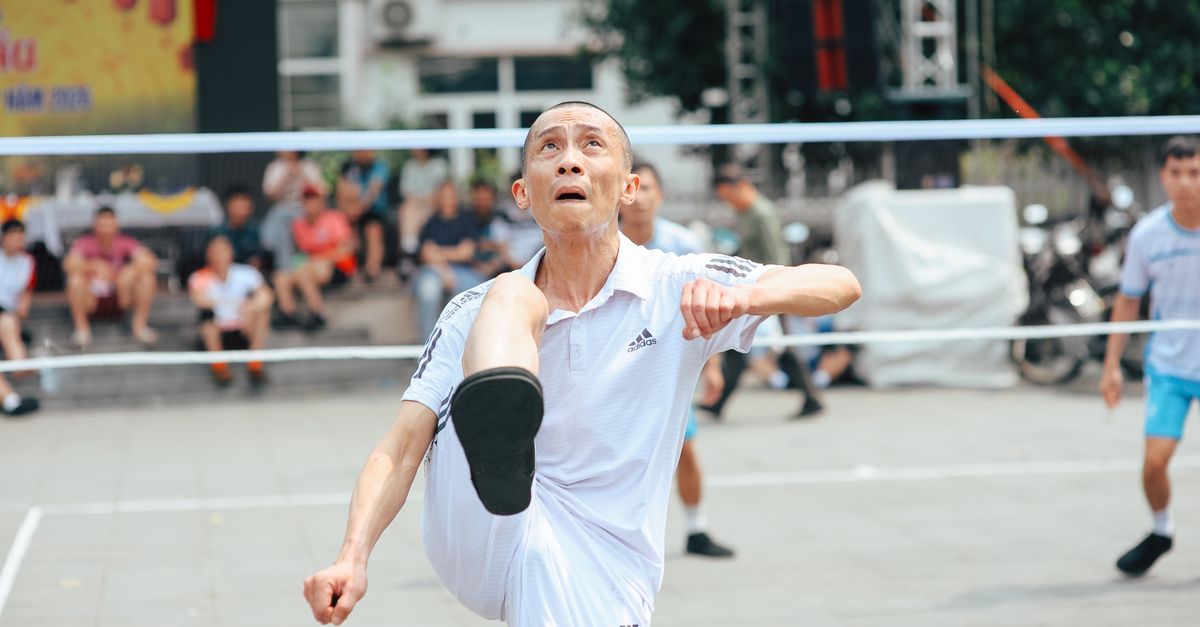 Elderly men playing kick volleyball outdoors on a sunny day.