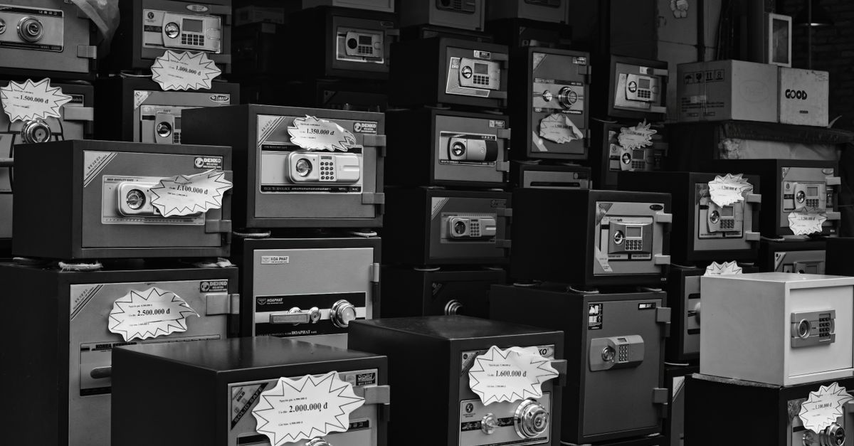 Monochrome photo of stacked safes with price tags in a store setting.