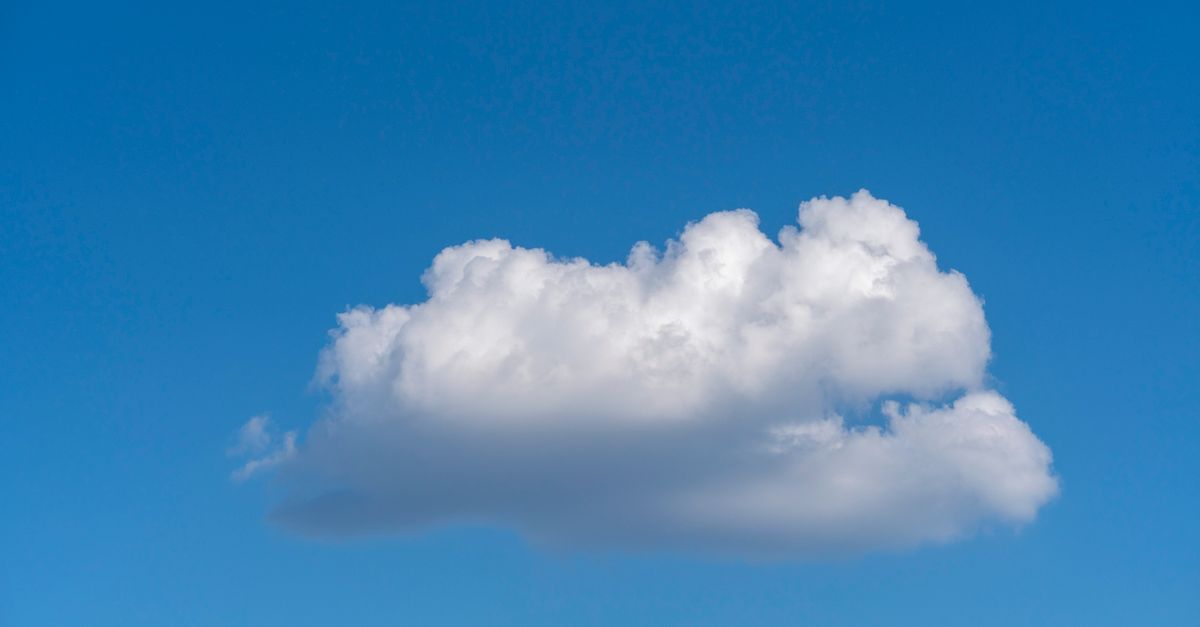 A single fluffy white cloud drifts against a clear blue sky, offering serene and peaceful vibes.