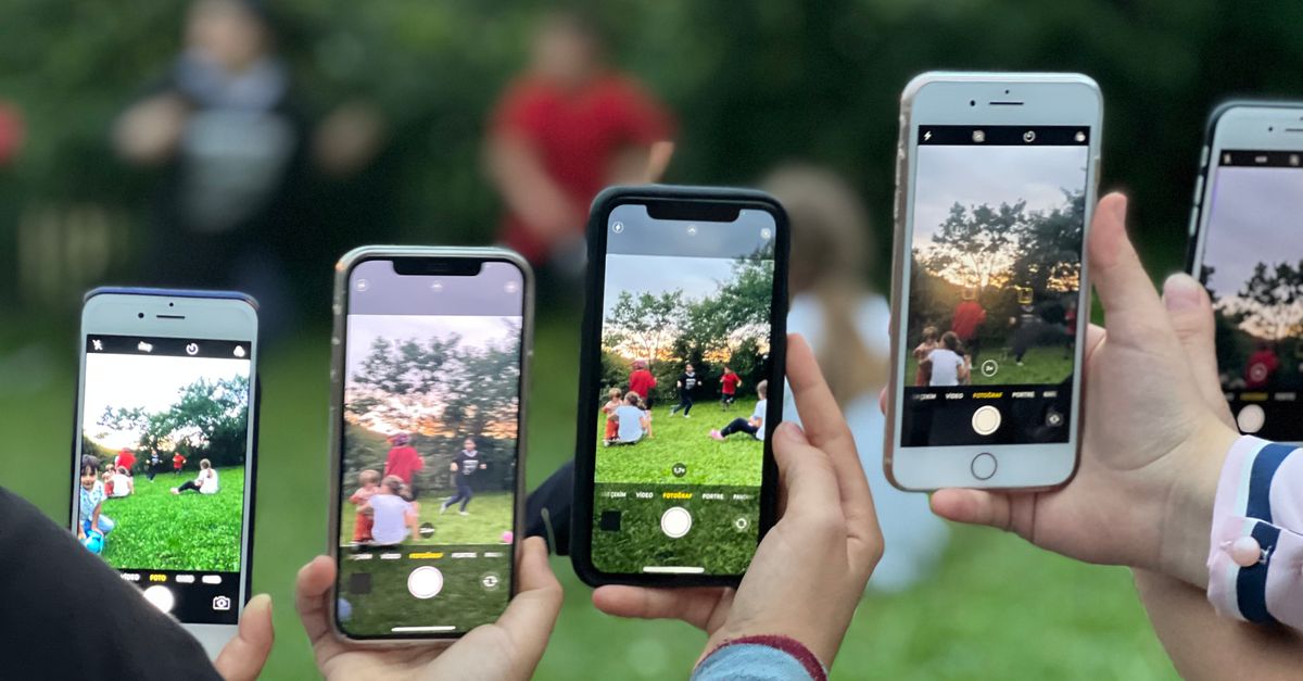 A group of people using smartphones to photograph an outdoor scene.