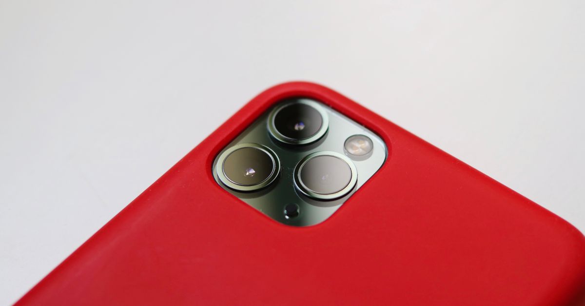 Macro shot of a smartphone camera with a red case, highlighting lens detail.