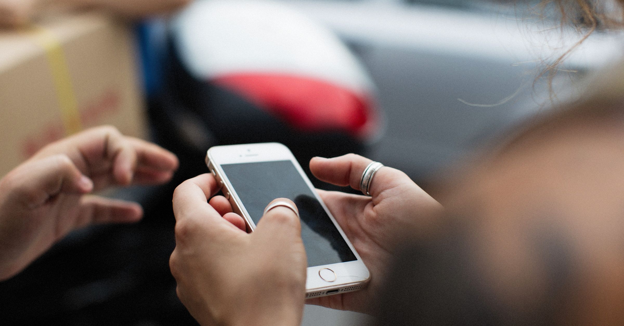 Person using a smartphone outdoors, accompanying a guide to who needs a private photo vault on iPhone.