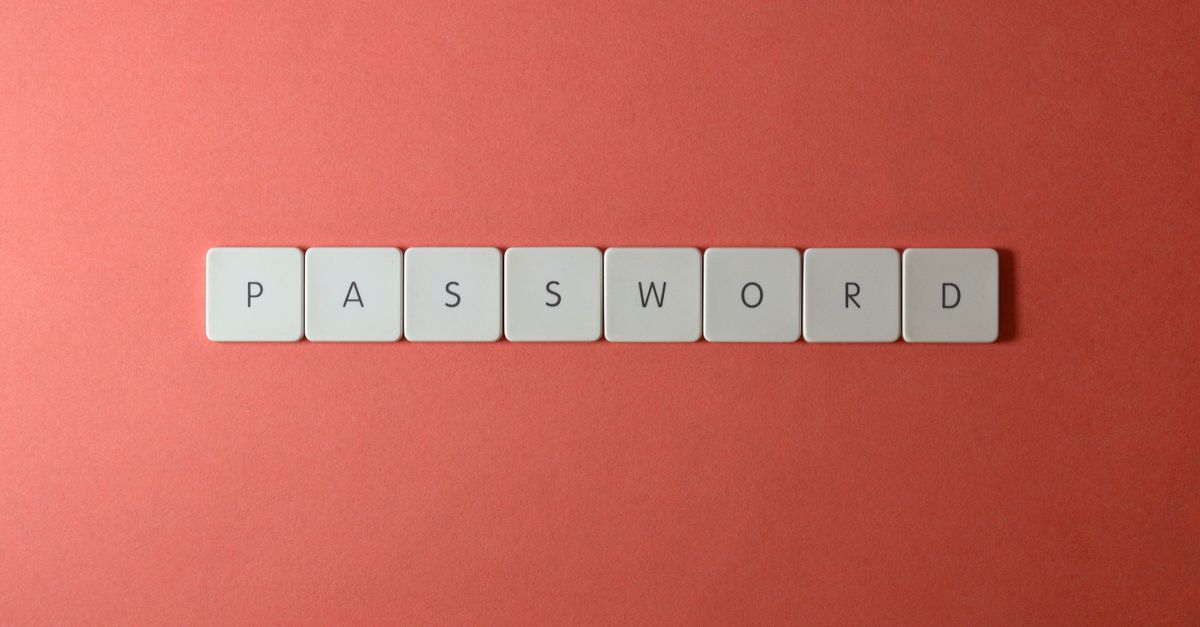 Focus on password security with white keyboard tiles spelling 'PASSWORD' on a coral background.